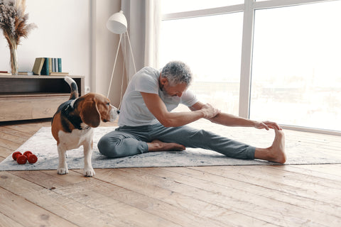 Senior man exercising at home near his dog